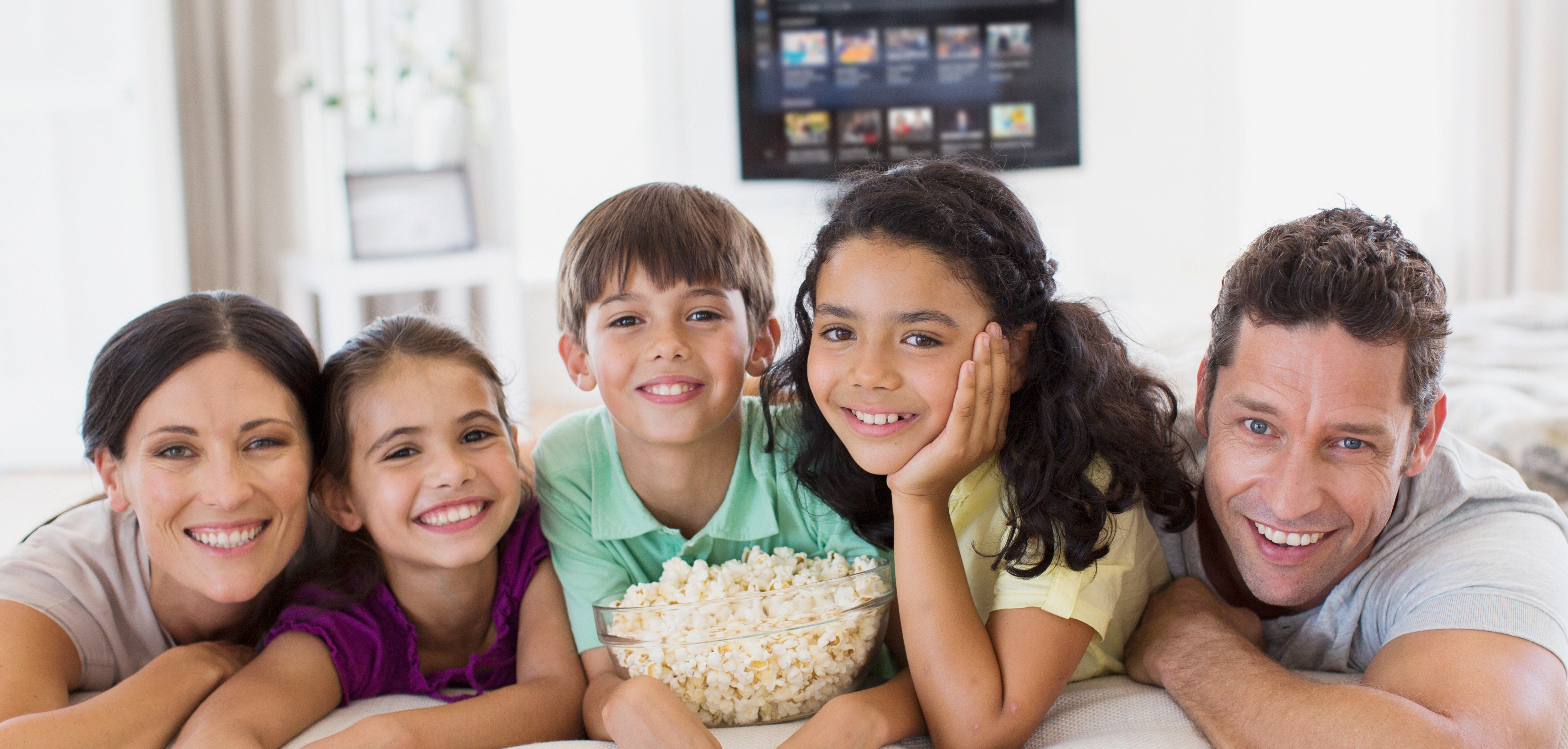 Familie sitzt mit Popcorn vor dem TV